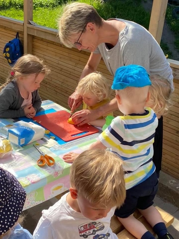En voksen tilbereder æbler med en gruppe piger